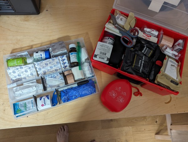a largeish med kit; visible contents include bandages, burn gel, peroxide, hand sanitizer, anti-diahreals, hydrocortisone, gauze, medical tapes, gloves, a sharpie, a tick key, a cpr mask, tourniquettes, cellox, pressure gauze, finger splints, ace bandages, carbomix, narcan, and EMT shears