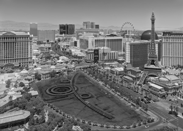 The Las Vegas Strip, looking north during the day, complete with fake Eiffel Tower, a ferris wheel, elaborate fountains, fake neoclassical buildings, a creepy glowing sphere, and absolutely nothing normally found in the middle of a desert.