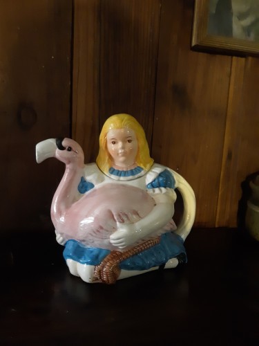 A teapot shaped like Alice, holding a pink flamingo from Alice in Wonderland.