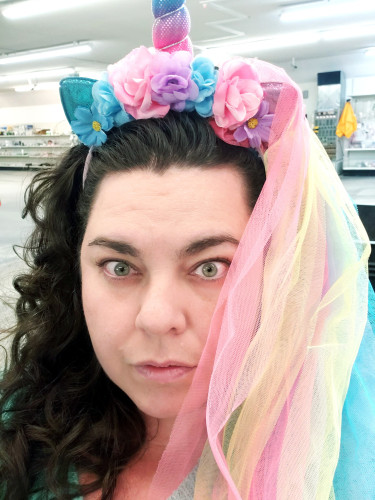 Me with a unicorn horn and flowers in my hair and an alarmed look on my face